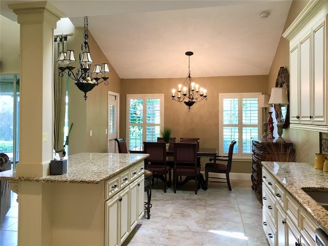 kitchen featuring light stone counters, a center island, an inviting chandelier, and vaulted ceiling