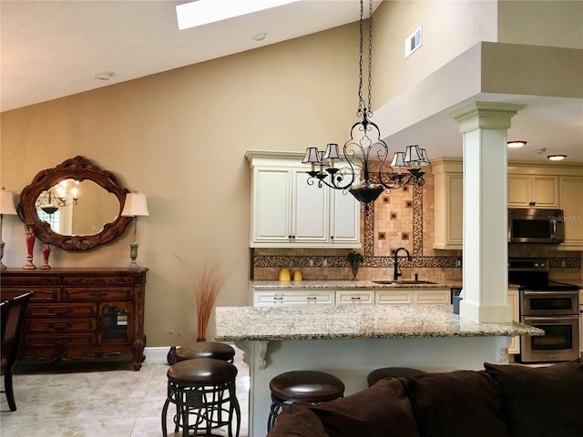 kitchen with sink, cream cabinetry, light stone counters, and appliances with stainless steel finishes