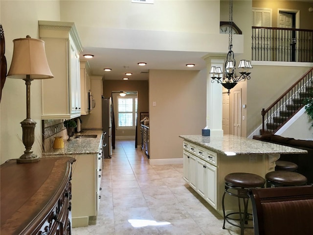 kitchen with a kitchen breakfast bar, hanging light fixtures, appliances with stainless steel finishes, light stone countertops, and a kitchen island