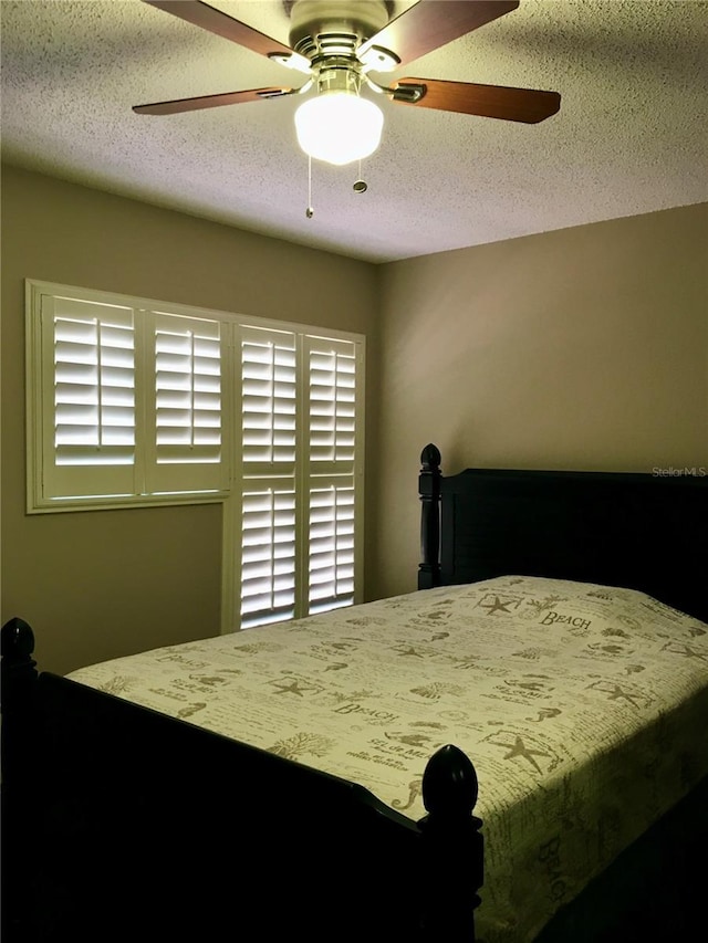 bedroom with multiple windows, a textured ceiling, and ceiling fan