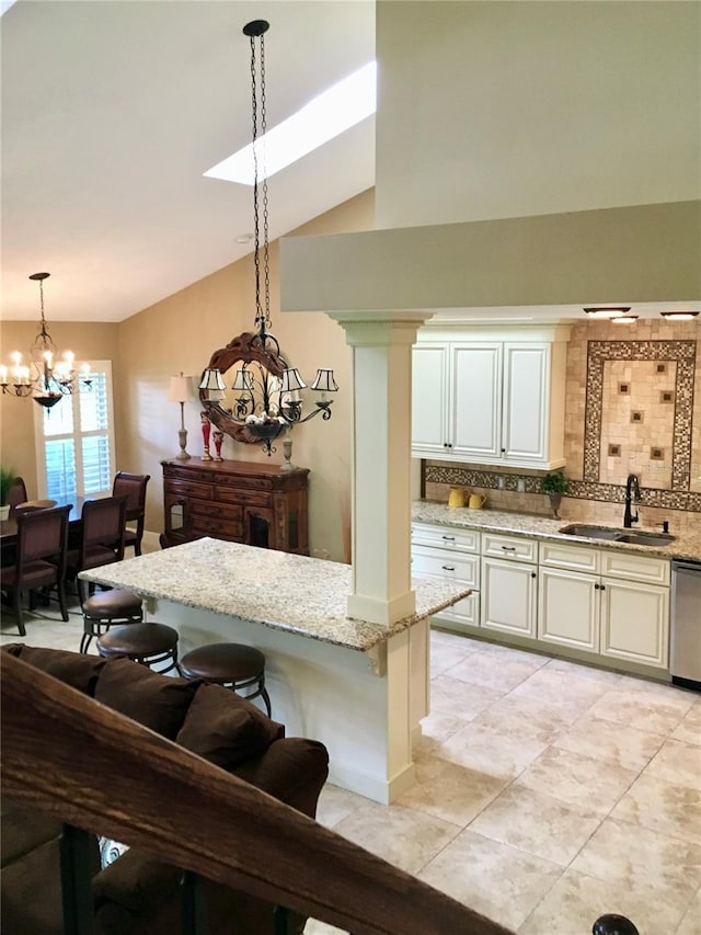 kitchen featuring vaulted ceiling, a chandelier, sink, decorative light fixtures, and backsplash