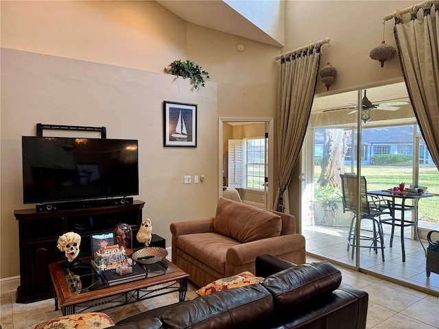 tiled living room with ceiling fan, a healthy amount of sunlight, and a high ceiling