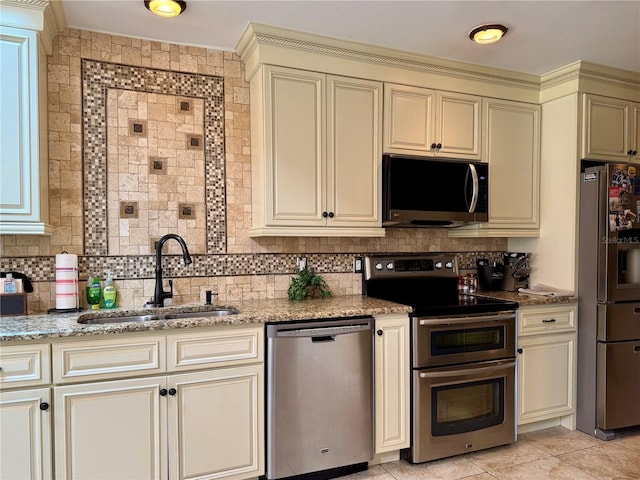 kitchen with stainless steel appliances, cream cabinets, sink, and backsplash