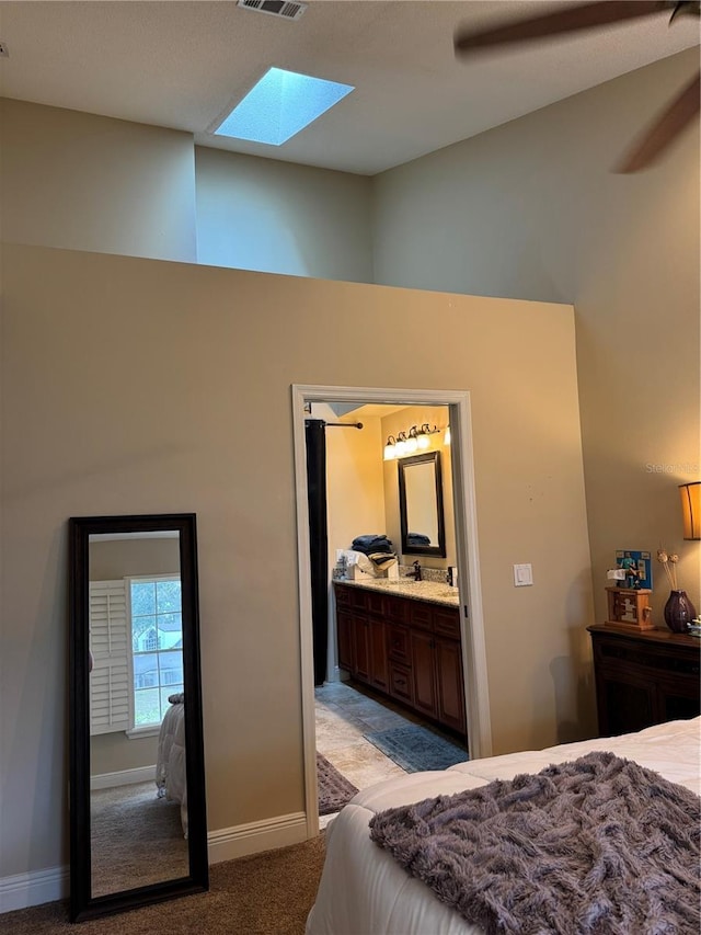 bedroom with light carpet, connected bathroom, a towering ceiling, and ceiling fan