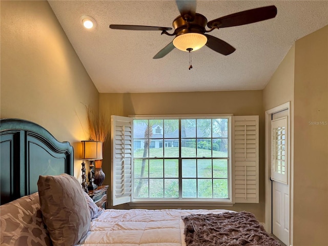 bedroom featuring ceiling fan, vaulted ceiling, and a textured ceiling