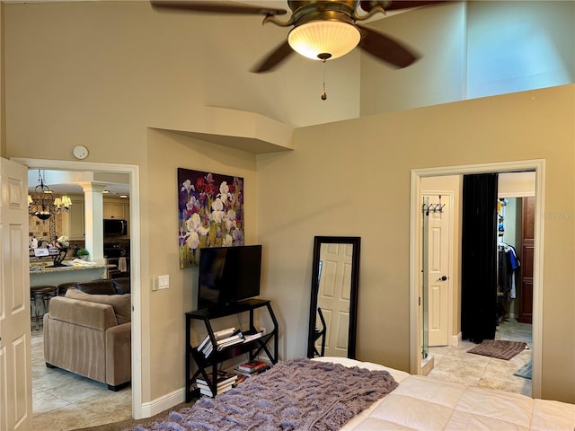 tiled bedroom with ceiling fan with notable chandelier, decorative columns, and a high ceiling