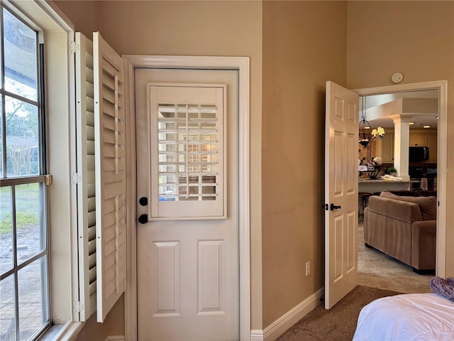 entryway featuring decorative columns and light carpet