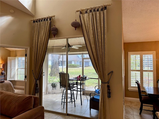 entryway with light tile patterned floors, a textured ceiling, and ceiling fan