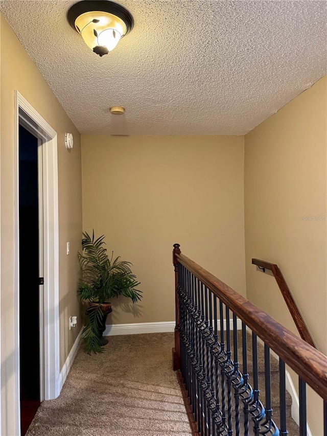 corridor with carpet floors and a textured ceiling