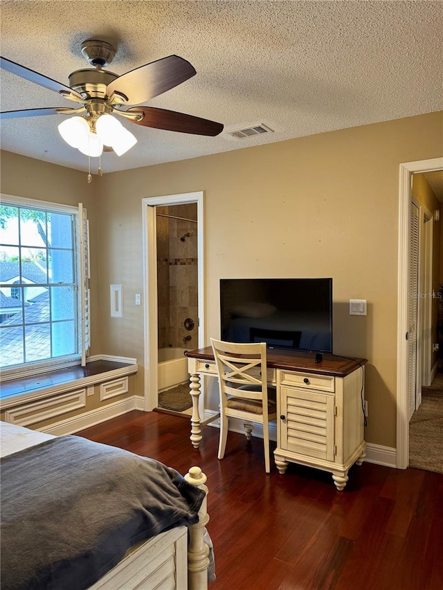 bedroom with ceiling fan, dark wood-type flooring, a textured ceiling, and ensuite bathroom