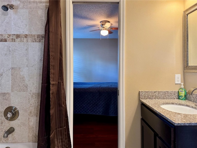 bathroom featuring vanity, ceiling fan, shower / tub combo, and a textured ceiling