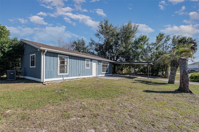 view of front of house featuring a front lawn, a carport, and central AC