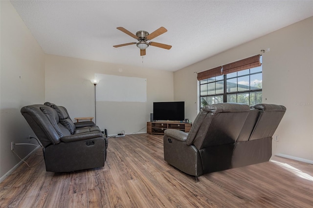 living room featuring ceiling fan, a textured ceiling, and wood-type flooring