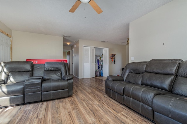 living room featuring ceiling fan, a textured ceiling, and wood-type flooring