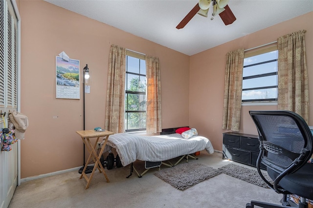 carpeted bedroom featuring multiple windows and ceiling fan