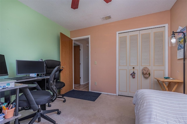 bedroom featuring light colored carpet, a textured ceiling, a closet, and ceiling fan