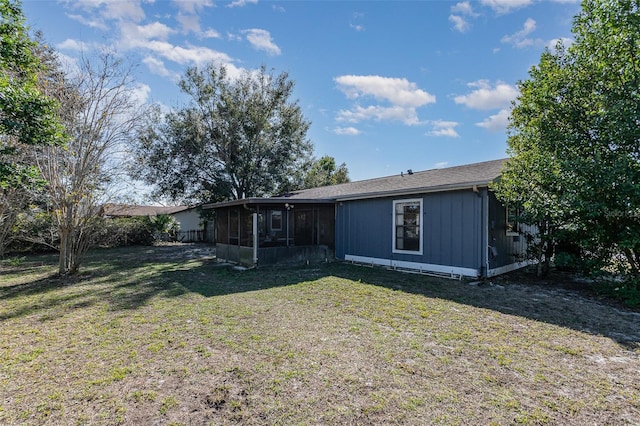 rear view of house featuring a lawn and a sunroom