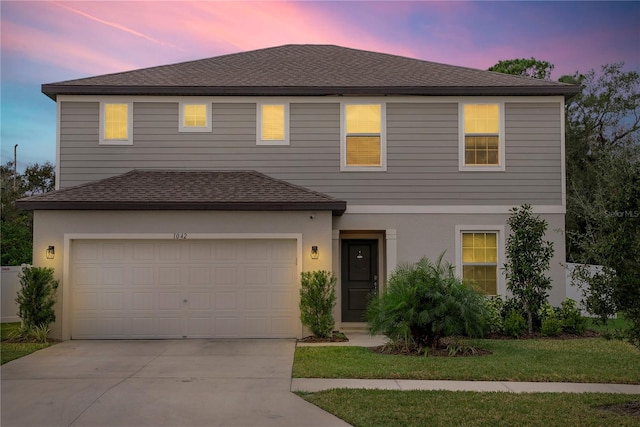 front of property with a garage and a yard