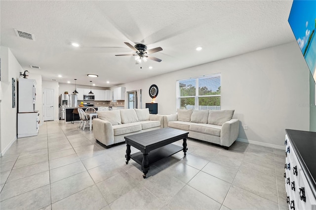 tiled living room with a textured ceiling and ceiling fan