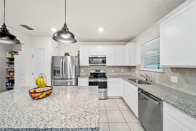 kitchen featuring sink, white cabinetry, a kitchen island, stainless steel appliances, and light stone countertops