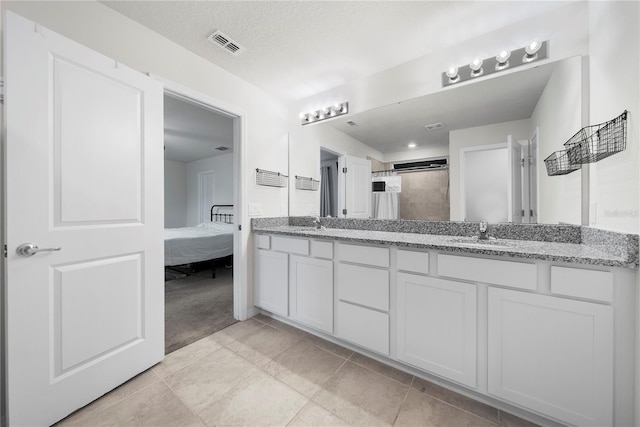 bathroom with vanity, a textured ceiling, and tiled shower