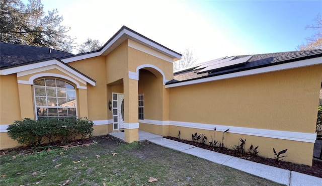 property entrance featuring a yard and solar panels