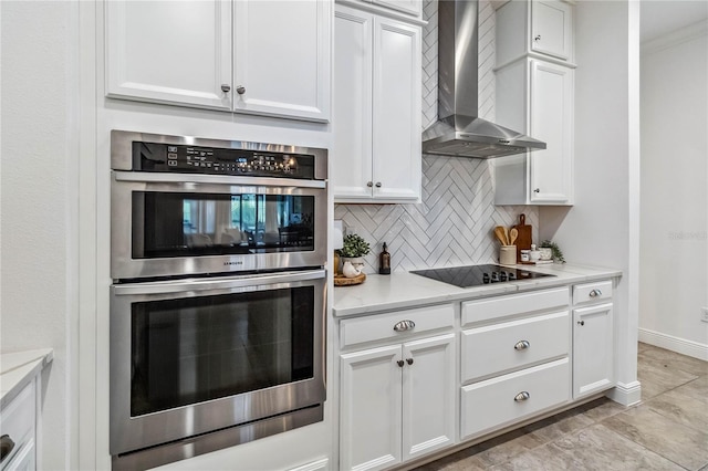 kitchen with stainless steel double oven, white cabinetry, and wall chimney exhaust hood