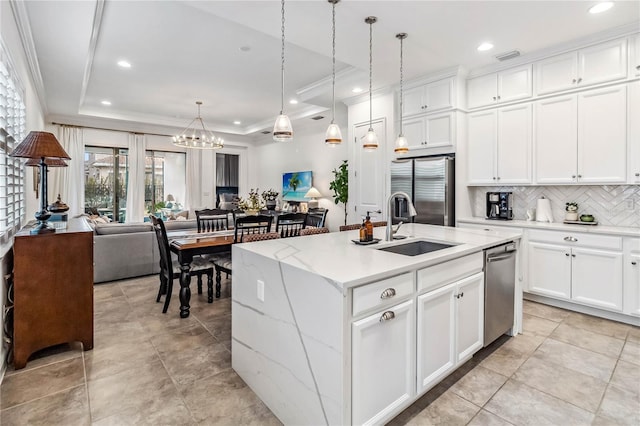 kitchen with a center island with sink, white cabinetry, a tray ceiling, and appliances with stainless steel finishes