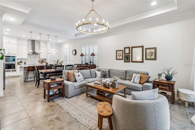 living room with light tile patterned floors, an inviting chandelier, a tray ceiling, and crown molding