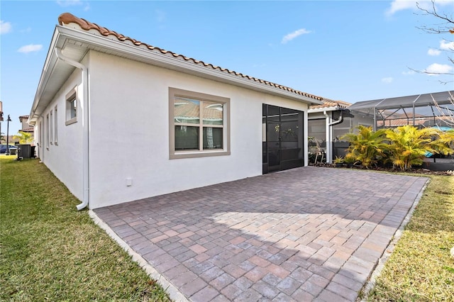 back of property with a patio, glass enclosure, and a lawn