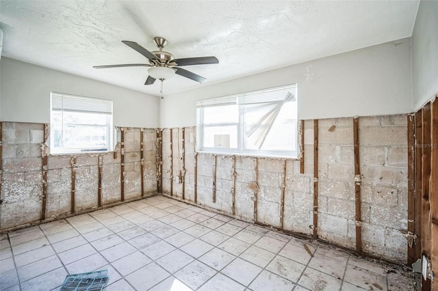 empty room with ceiling fan and a textured ceiling