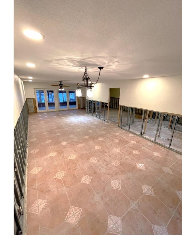 basement featuring ceiling fan with notable chandelier and a textured ceiling