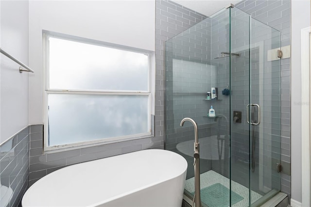 bathroom featuring plus walk in shower and tile walls