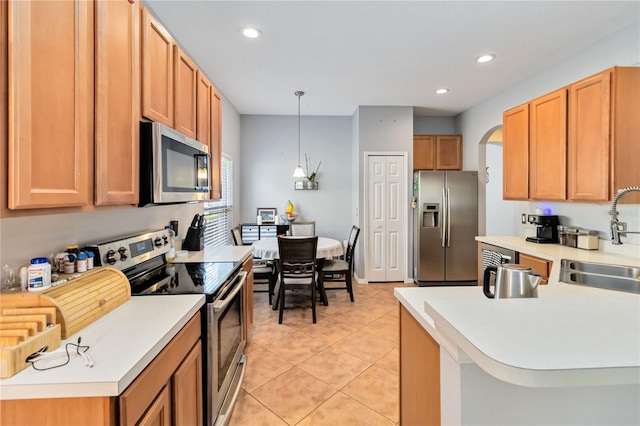 kitchen featuring appliances with stainless steel finishes, sink, light tile patterned floors, and decorative light fixtures