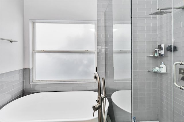 bathroom featuring shower with separate bathtub and tile walls