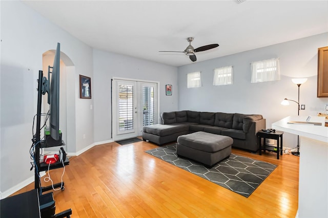 living room featuring wood-type flooring, ceiling fan, and french doors