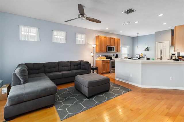 living room with ceiling fan and light hardwood / wood-style flooring