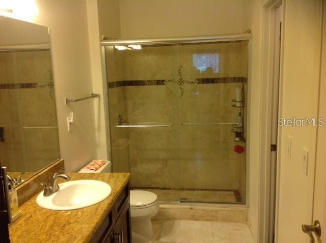 bathroom featuring walk in shower, tile patterned floors, vanity, and toilet