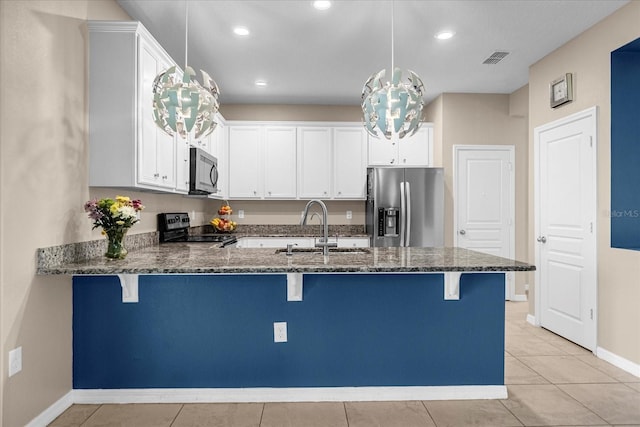 kitchen featuring pendant lighting, stainless steel appliances, a breakfast bar area, dark stone countertops, and sink