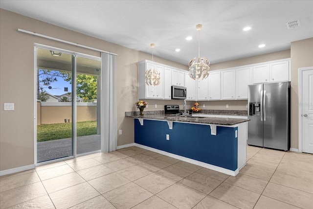 kitchen featuring white cabinets, appliances with stainless steel finishes, a breakfast bar area, and hanging light fixtures