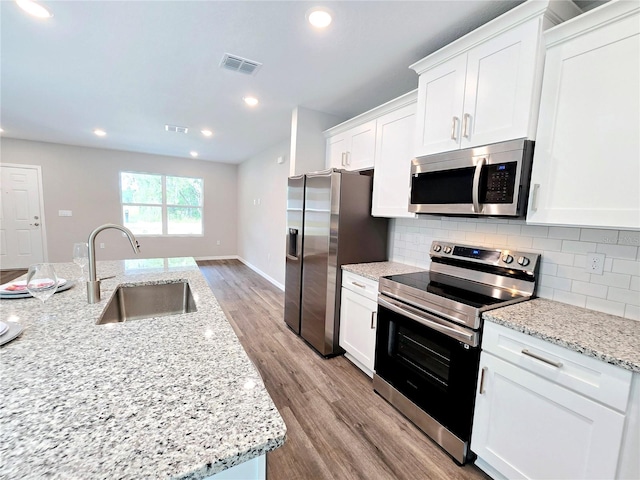 kitchen with sink, stainless steel appliances, white cabinets, and light stone countertops