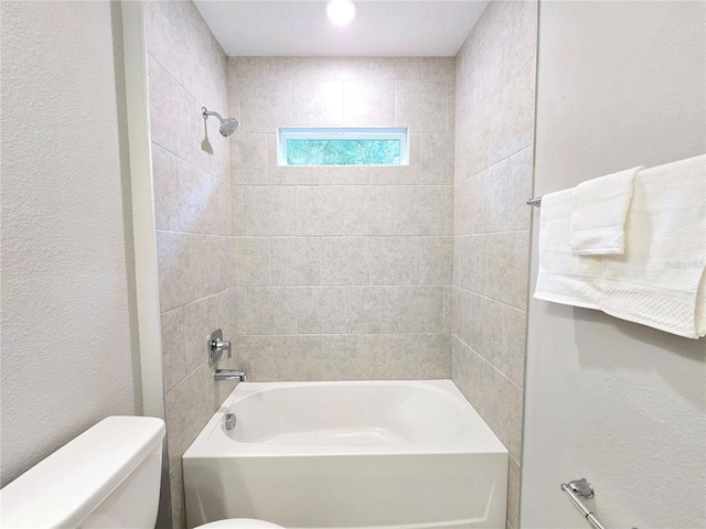 bathroom with toilet and tiled shower / bath