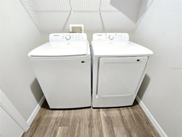 laundry room featuring washing machine and clothes dryer and hardwood / wood-style floors