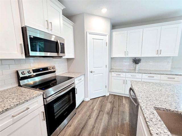 kitchen featuring light stone counters, light hardwood / wood-style flooring, stainless steel appliances, backsplash, and white cabinets