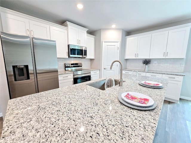 kitchen featuring sink, stainless steel appliances, white cabinetry, and light stone countertops