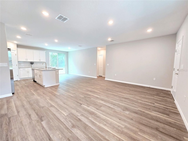 kitchen featuring light hardwood / wood-style flooring, an island with sink, white cabinets, appliances with stainless steel finishes, and sink