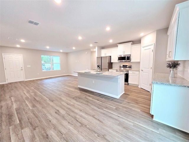 kitchen featuring light stone counters, an island with sink, light hardwood / wood-style floors, white cabinetry, and appliances with stainless steel finishes