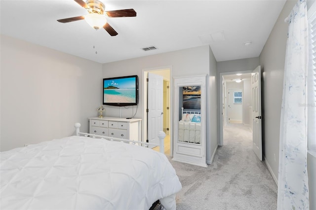 bedroom with ensuite bathroom, light colored carpet, and ceiling fan