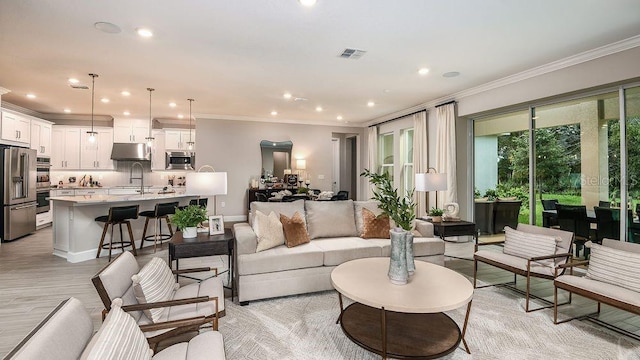 living room featuring crown molding, light hardwood / wood-style flooring, and sink