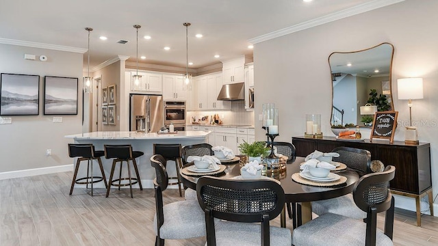 dining area with ornamental molding and light hardwood / wood-style floors